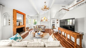 Un salón amplio con chimenea, televisor grande y una escalera que sube a un nivel superior.