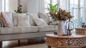 Una sala de estar con un sofá, una mesa redonda de centro y un jarrón decorativo.