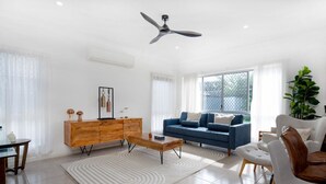 Un salon moderne avec un canapé bleu, un buffet en bois et un ventilateur de plafond.
