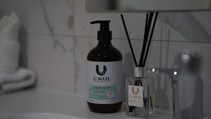 A bathroom with a U MATE liquid soap bottle and a U MATE reed diffuser. - Modern 1BR Apartment | Convenient Stay (MacGregor)