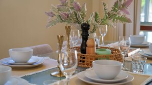 A dining table set with white plates, bowls, and glasses, accompanied by a salt and pepper set, a decorative plant, and a woven basket. - Modern 4BR Family Retreat | Prime Robertson Place (Robertson)