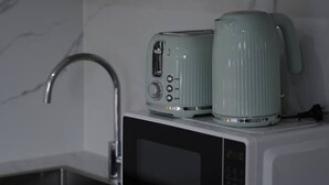 A modern kitchen with a built-in microwave, a kettle, and a toaster on the countertop. - Modern Private Retreat | Perfect for Solo Traveler (MacGregor)