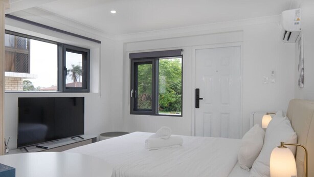 A modern bedroom with a large bed, a TV, and a desk. - Modern Private Retreat | Perfect for Solo Traveler (MacGregor)
