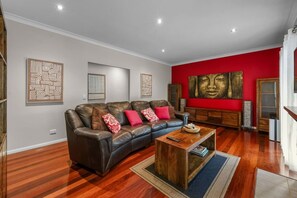 A living room with a leather sofa, a coffee table, and a red accent wall. - Modern Japanese Retreat in Tamborine Mountain (Tamborine Mountain)