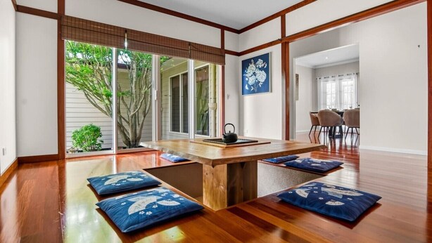 Een traditionele Japanse kamer met tatami matten, een lage houten tafel en uitzicht op een tuin.