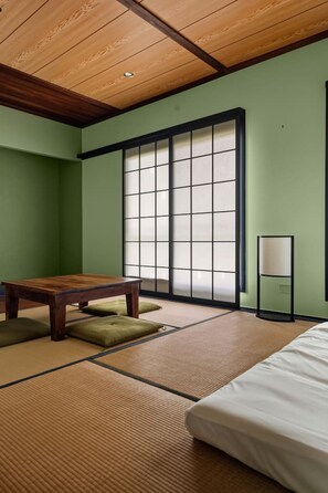 Une pièce traditionnelle japonaise avec un sol recouvert de tatamis, une basse table en bois, un lit et une porte coulissante en papier de riz (shoji).