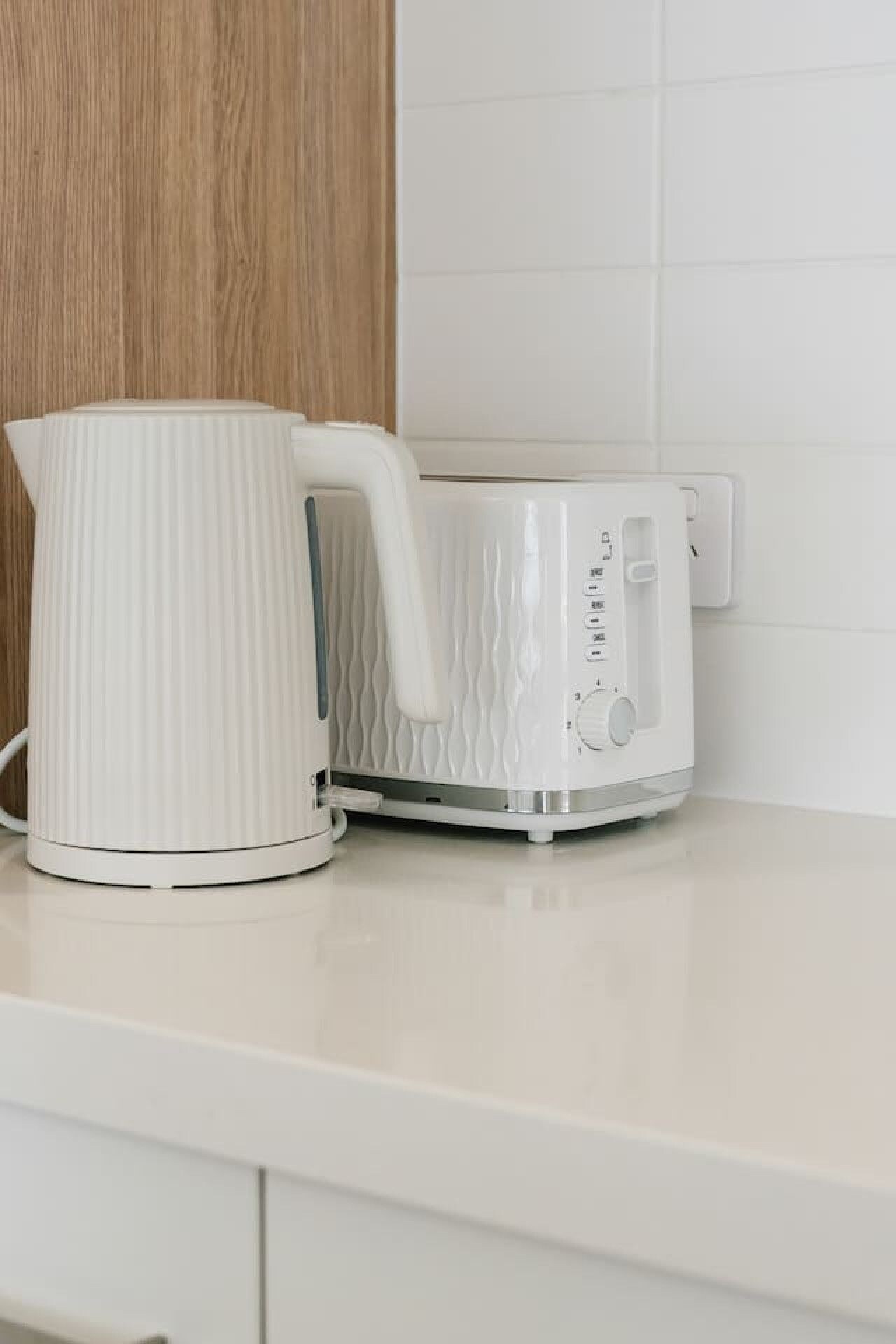 A white kettle and a white electric kettle on a white countertop.