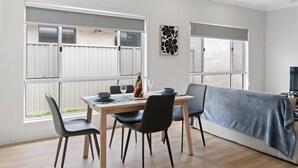 A modern dining area with a wooden table, black chairs, and a Christmas tree.
