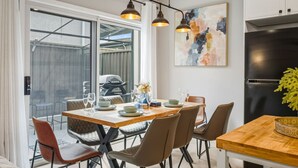 Et moderne køkken med spiseplads, store vinduer og et sort køleskab.