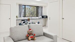 A modern living room with a grey sofa and a teddy bear wearing a Santa hat. - Cozy Little Charm Unit in Eight Miles Plain (Eight Mile Plains)
