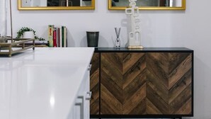 A modern bathroom with a white vanity, two gold-framed mirrors, and a herringbone-patterned cabinet. - Elegant 4BR Residence |Friendly Haven in Calamvale (Calamvale)