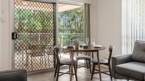A balcony with a table set for two, a chair, and a sofa. - Charming 2BR Home in Serene Mount Warren Park (Mount Warren Park)