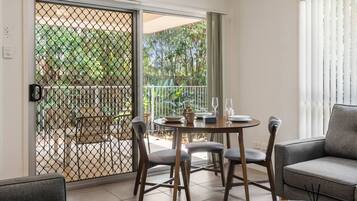A balcony with a table set for two, a chair, and a sofa.