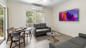 A modern living room with a grey sofa, a round coffee table, and a dining table with chairs. - Charming 2BR Home in Serene Mount Warren Park (Mount Warren Park)