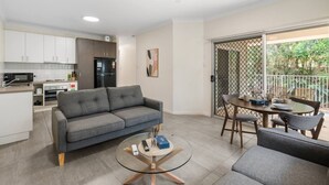 A modern living area with a sofa, coffee table, and dining set. - Charming 2BR Home in Serene Mount Warren Park (Mount Warren Park)