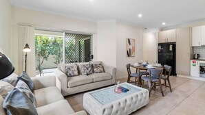 A modern living room with a sofa, ottoman, and dining area with chairs and a table.