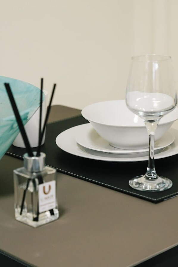 A table set with a white plate, a glass, and a bottle of perfume. - Affordable Comfort | Cozy Stay with All Essentials (Eight Mile Plains)
