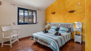 A bedroom with a bed, a chair, a nightstand, a lamp, and a window with a view. - Unit 1 with Sea View, Shared Terrace and Wi-Fi (Yaiza)