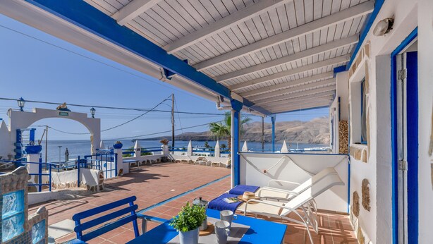 A covered outdoor seating area with a table, chairs, and a potted plant.
