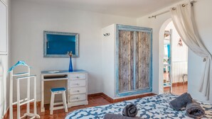 A bedroom with a bed, a desk, a wardrobe, and a mirror.