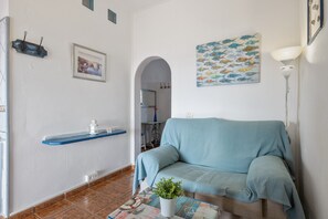 A living room with a sofa, a coffee table with a plant, a wall-mounted shelf, and a painting. - Unit 4 at "Ventanas de Lanzarote" with Wi-Fi and Shared Terrace with Sea Views (Yaiza)