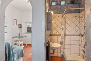 Een badkamer met een wastafel, douche en betegelde wanden.