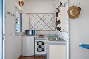 Een kleine keuken met een magnetron, spoelbak en een kleine koelkast.