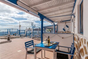Una terrazza con un tavolo, sedie e una bottiglia di vino.