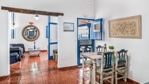 Ein Zimmer mit Esstisch, Stühlen, einem Spiegel und einer blauen Tür.
