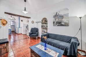 Een woonkamer met een bank, een salontafel, een boekenkast, een stoel en een lamp.
