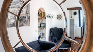 Ein Zimmer mit einem runden Spiegel, der einen Wohnbereich, ein Bücherregal, einen Garderobenständer und eine Tür zu einem anderen Raum reflektiert.