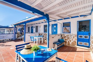 A covered outdoor seating area with blue furniture, a stone wall, and a blue door. - Unit 5 'Ventanas de Lanzarote' with Shared Terrace and Wi-Fi (Yaiza)