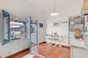 A kitchen with a dining area, a window with blue trim, and a view of the outside. - Unit 6 'Ventanas de Lanzarote' with Shared Terrace and Wi-Fi (Yaiza)