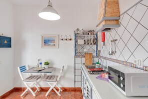 A compact kitchen with a microwave, sink, and a dining area with chairs and a table. - Unit 6 'Ventanas de Lanzarote' with Shared Terrace and Wi-Fi (Yaiza)