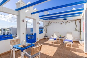 Una terraza con una mesa, sillas y macetas.