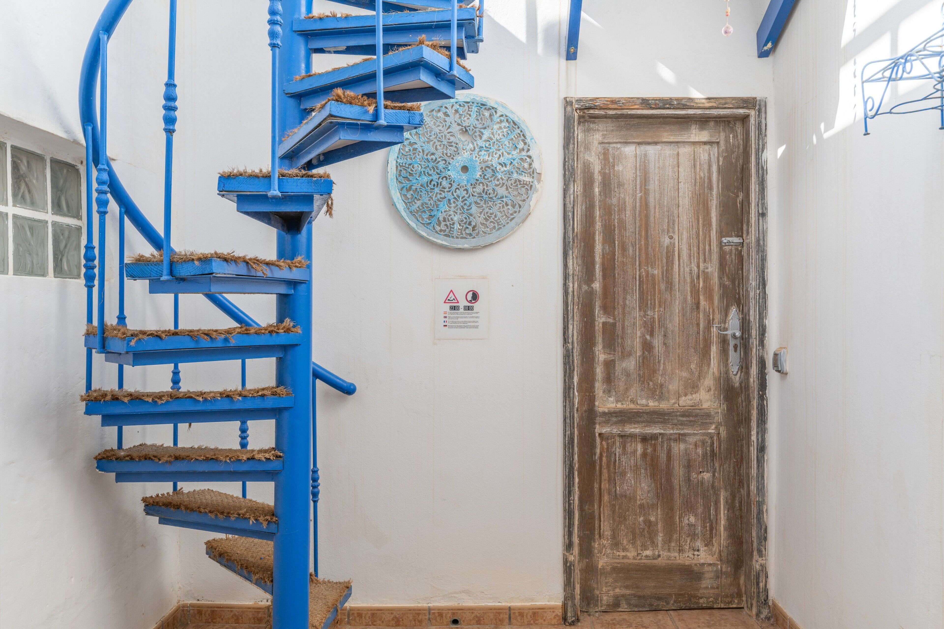 A spiral staircase with blue railings and a wooden door.