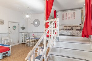 Una habitación con una cama individual, un escritorio, una silla y una mesita.