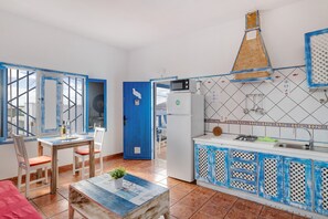 Une cuisine avec une porte bleue, des armoires blanches et un mur recouvert de carreaux.