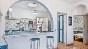 Una cucina con una grande isola, due sgabelli, un forno a microonde e un fornello.