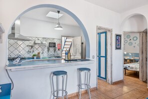 Een keuken met een groot eiland, twee krukken, een magnetron en een fornuis.
