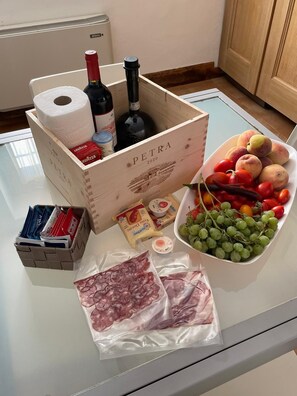 A kitchen counter with a wooden crate labeled "PETRA 2020," containing wine bottles, a roll of paper towels, and a basket of snacks. - PODERE AURORA (Massa Marittima)