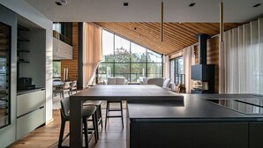 Eine moderne Küche mit einer großen Kochinsel, Holzboden und großen Fenstern mit Blick ins Freie.