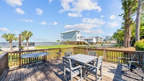 A wooden deck with a table and chairs, overlooking a body of water and a residential area. - Wolf Bay Villas 208 (Orange Beach)