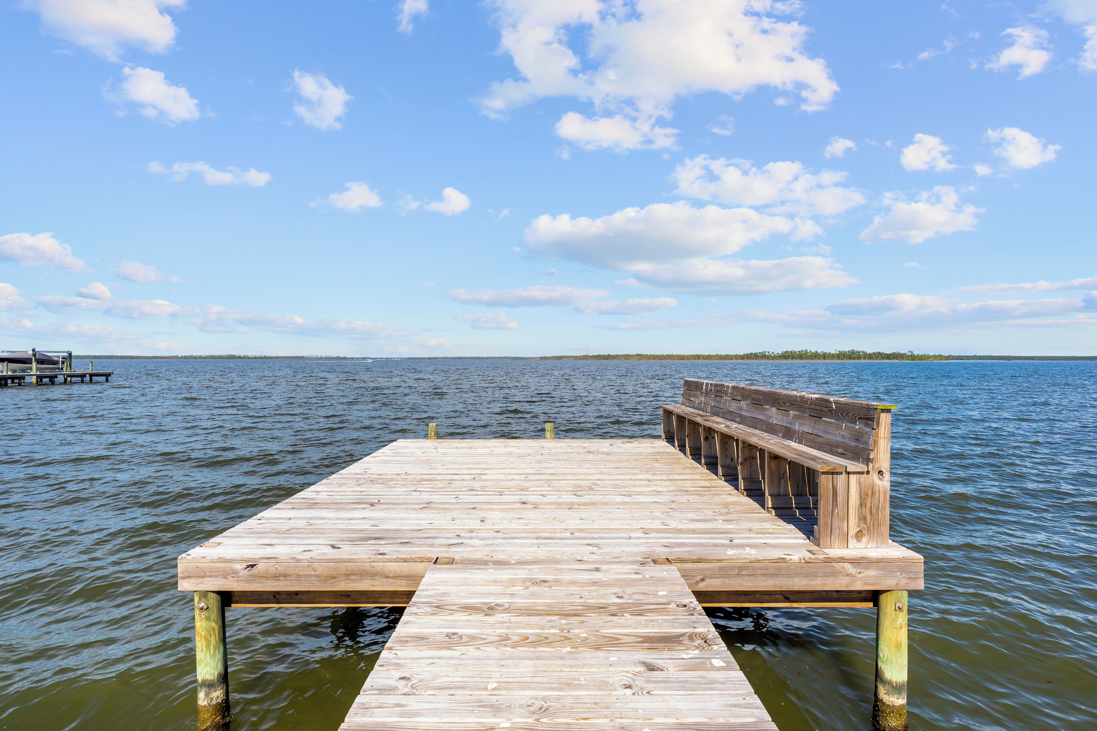 Un muelle de madera que se adentra en aguas tranquilas bajo un cielo despejado.