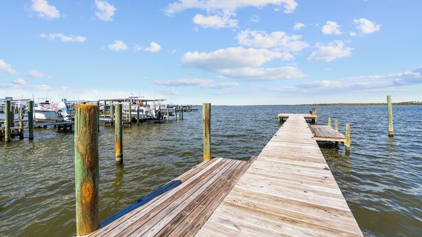A wooden pier extending into calm waters with boats docked at the marina. - Wolf Bay Villas 208 (Orange Beach)