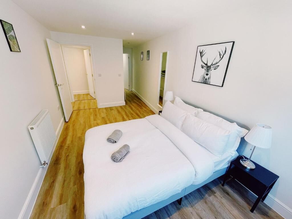 Une chambre à coucher avec un lit, une table de chevet, une lampe et un tableau encadré au mur.