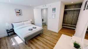 Ein modernes Schlafzimmer mit Bett, Nachttisch und einer kleinen Pflanze auf dem Nachttisch.