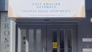 Ein Gebäudeeingang mit einem Schild für East Anglian Getaways Prosper House Apartments.