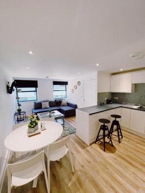 Un appartement moderne comprenant un coin repas, une cuisine et un salon.