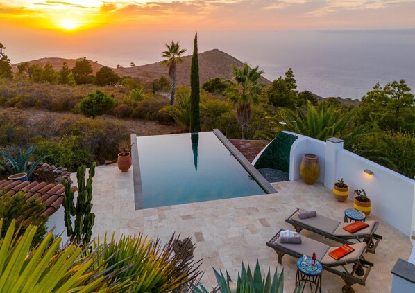Piscina no terraço com espreguiçadeiras e plantas em vasos.